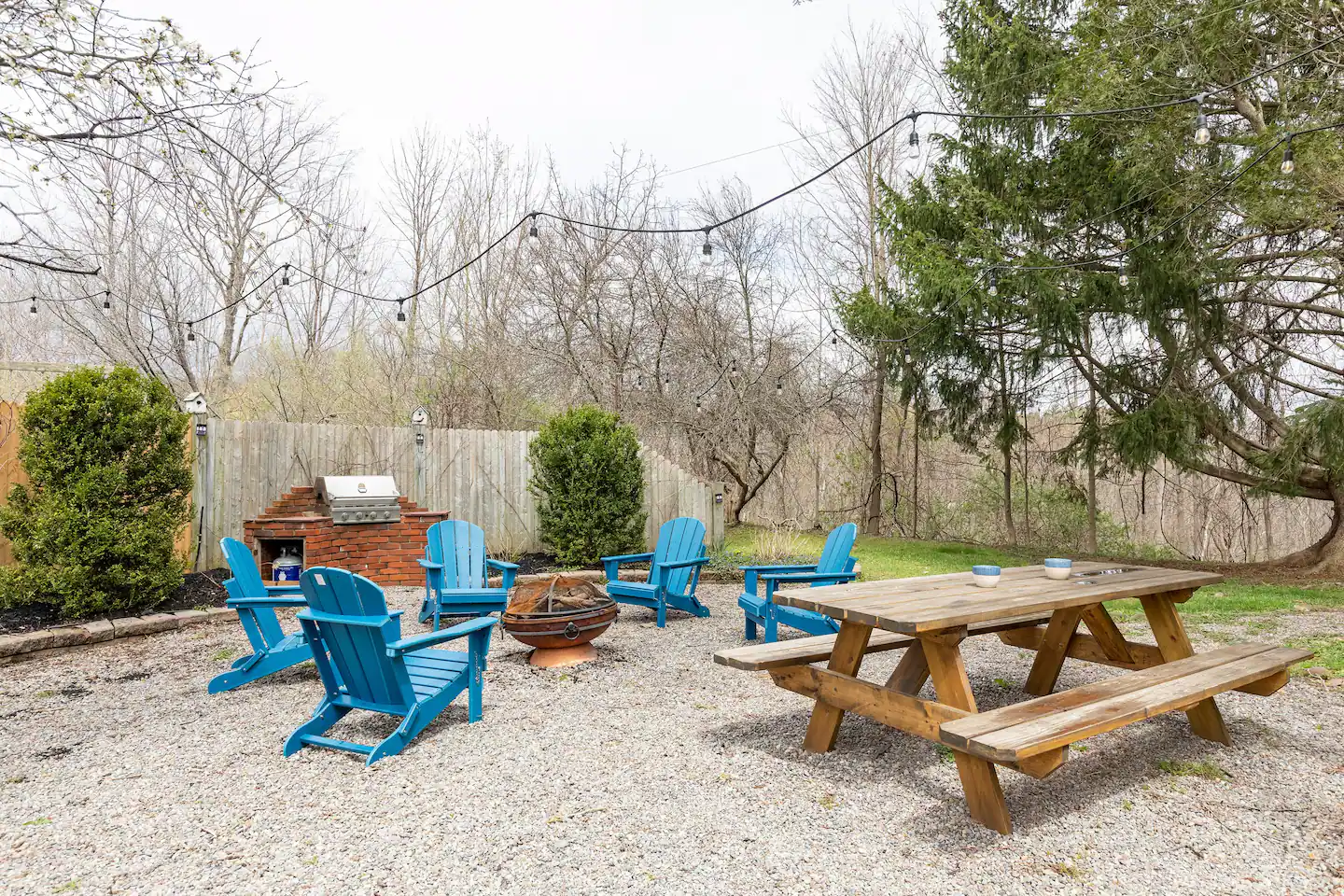 Firepit seating with blue Adirondack chairs and a picnic table